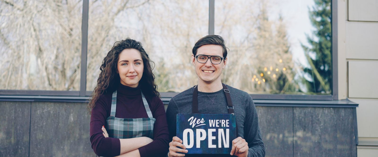 Small business owners holding an open sign